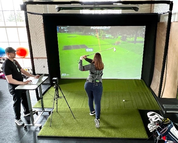 Woman hitting a golf ball wearing K-Vest to track golf swing